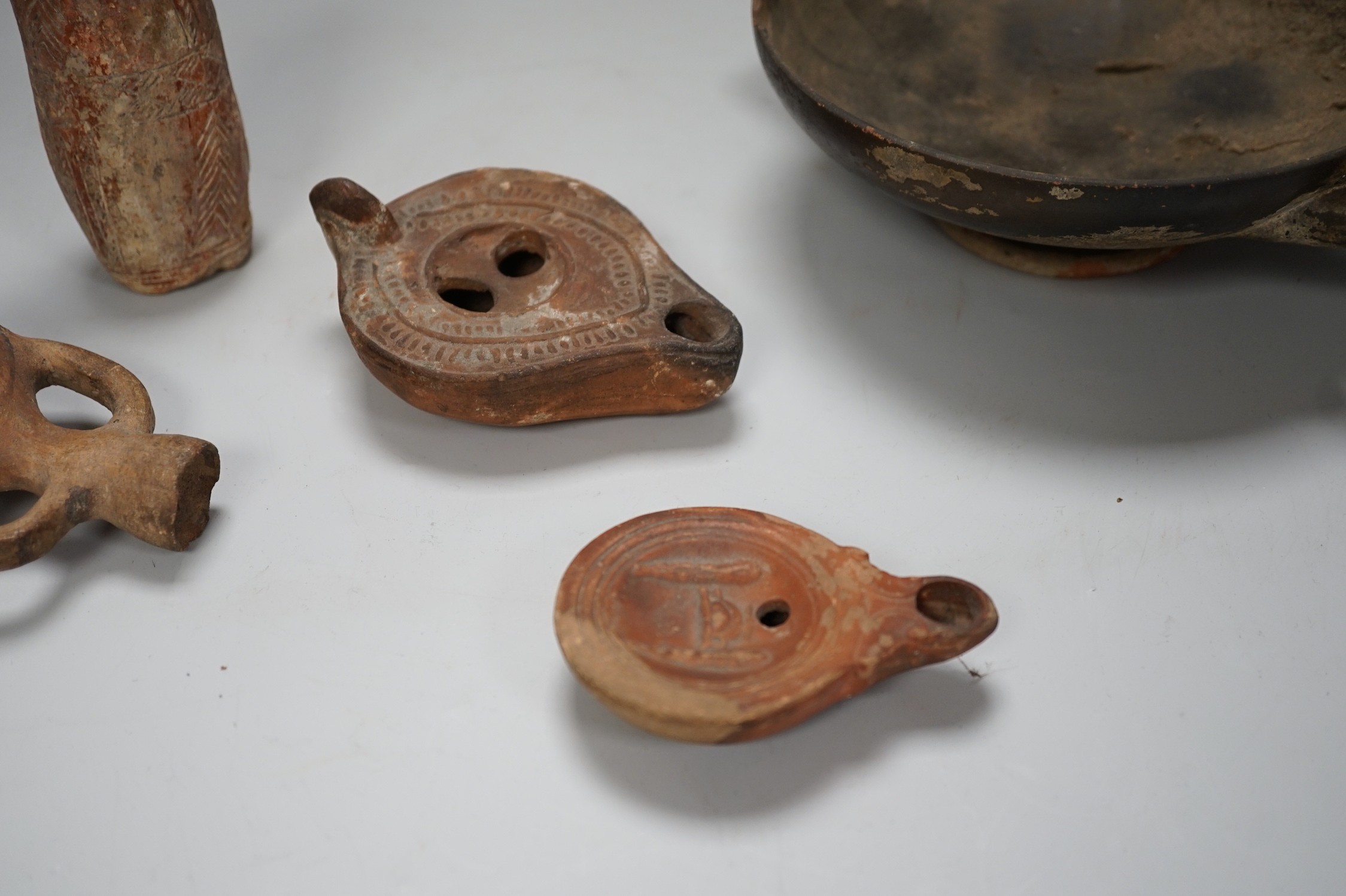 An Apulian black painted kylix, c. 4th century BCE., a Cypriot pottery flask, early Iron Age, two Roman terracotta oil lamps and another archaic vessel, tallest 14cm